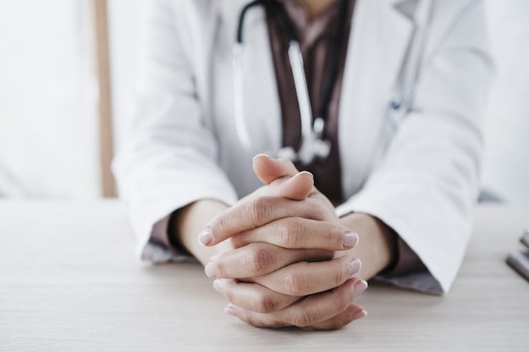 Female doctor with hands clasped in medical clinic