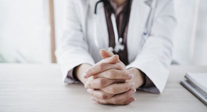 Female doctor with hands clasped in medical clinic
