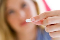 Photo: Getty Images Depressed young woman taking pills at home.