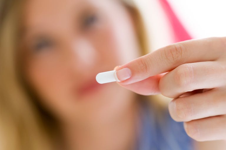 Photo: Getty Images Depressed young woman taking pills at home.
