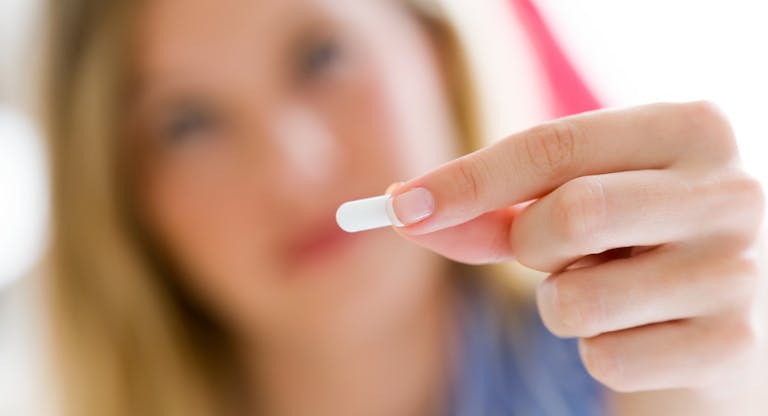 Depressed young woman taking pills at home.