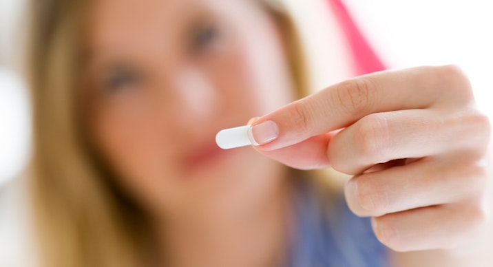 Depressed young woman taking pills at home.