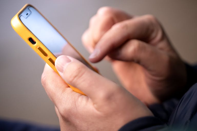 Smartphone in male hands. Close up of hands with a phone. Outdoor photo Using a smartphone