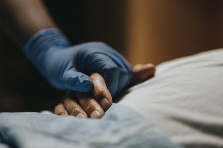Photo: Maskot (via Getty Images) Medical staff wearing surgical glove holding hand of patient at clinic