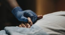 Medical staff wearing surgical glove holding hand of patient at clinic