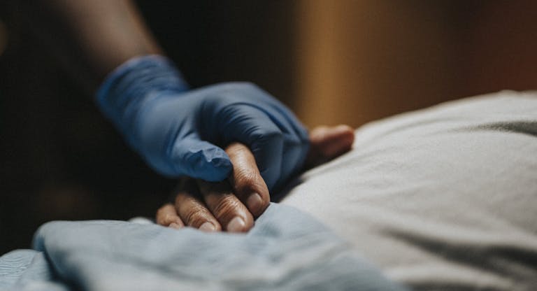 Medical staff wearing surgical glove holding hand of patient at clinic