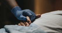 Medical staff wearing surgical glove holding hand of patient at clinic
