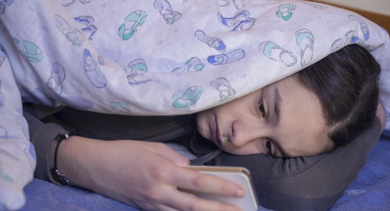 Photo of Girl using phone in bed during the day