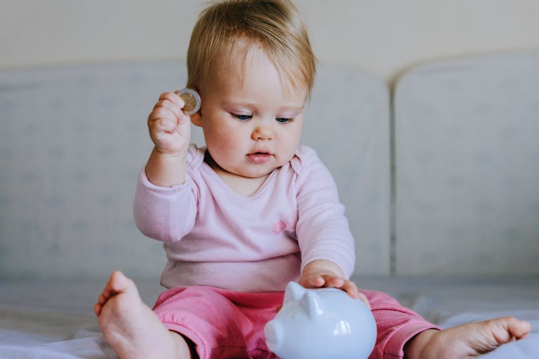 Baby girl  putting one coin into piggy bank. Baby girl  putting one coin into piggy bank.