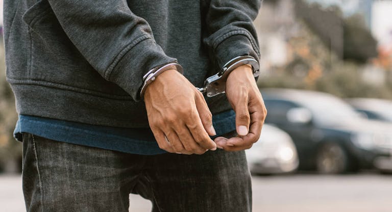 Save to BoardLooking down at handcuffed male hands on black background