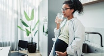 Pregnant Woman Drinking Water in Modern Kitchen Setting