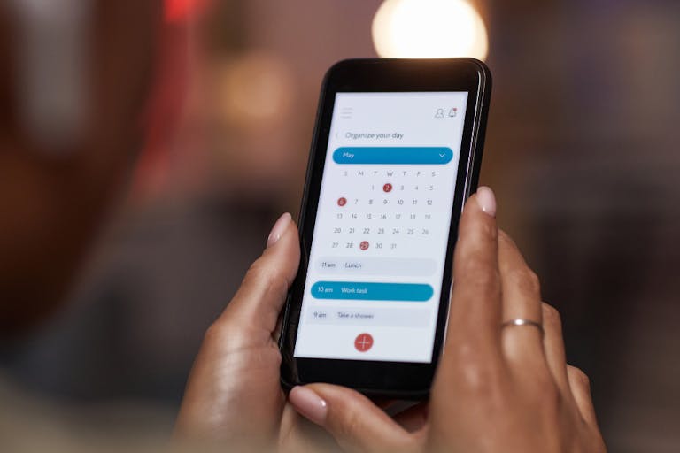 Close-up of woman using online calendar on mobile phone to plan her week Woman planning her week