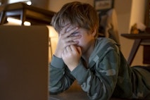 Young kid looking movies on the laptop at home Young kid looking movies on the laptop