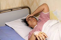 Indian woman feeling sick and suffering from a headache, lying down on the patient bed in the hospital and taking a rest portrait close up. Indian woman feeling sick and suffering from a headache, lying down on the patient bed in the hospital and taking a rest.