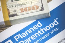 An editorial stock photo of planned parenthood informational document with a stack of $10,000 to illustration the cost of Planned Parenthood or other related health care services. Please note the money is not real and is marked with the words "for motion picture use only" Planned Parenthood Document
