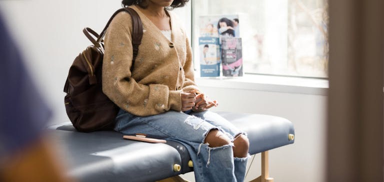 Distraught teen girl waits in doctor’s examination room