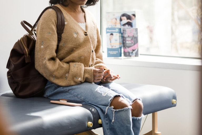 The teen girl, under tremendous emotional stress, waits in the doctor's examination room. Distraught teen girl waits in doctor’s examination room