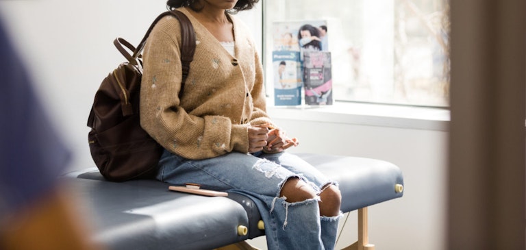 Distraught teen girl waits in doctor’s examination room