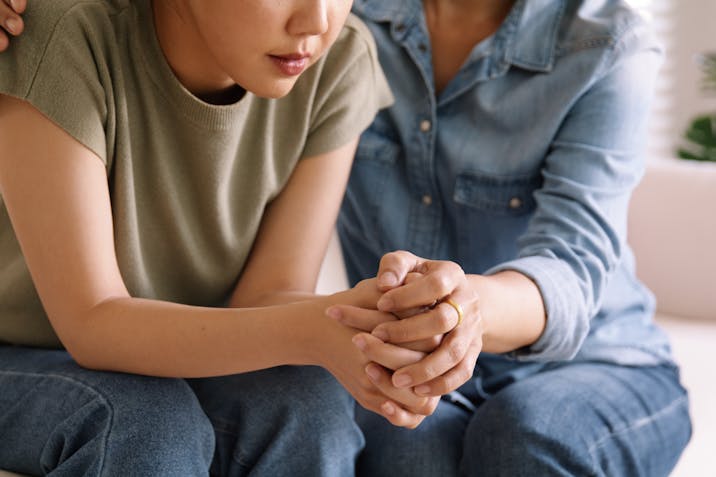 Middle aged asia people old mom holding hands trust comfort help young woman talk crying stress relief at home. Mum as friend love care hold hand adult child feel pain sad worry of life crisis issues. An older woman sitting next to a younger woman, holding her hand in comfort