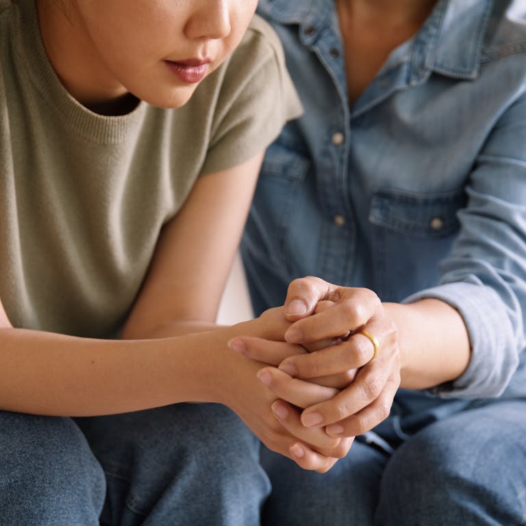 Photo: Getty Images An older woman sitting next to a younger woman, holding her hand in comfort