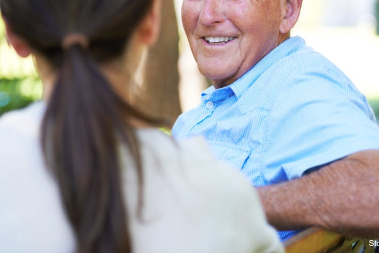 A lovely woman enjoying a conversation with her senior father outdoors Enjoying one another’s company