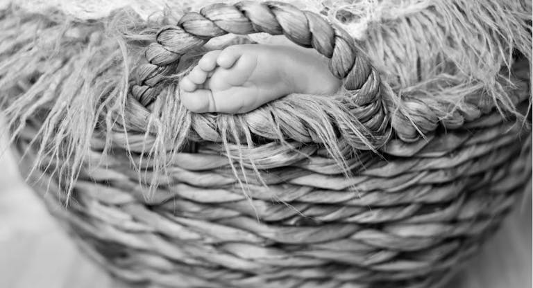 Close up picture of new born baby feet on a white plaid in the wicker basket