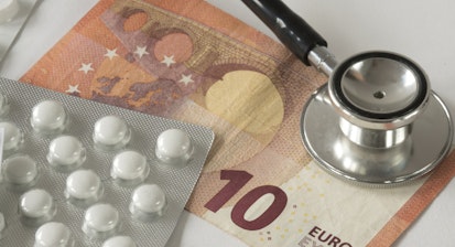 Assorted pharmaceutical medicine pills, tablets, stethoscope and money against white background