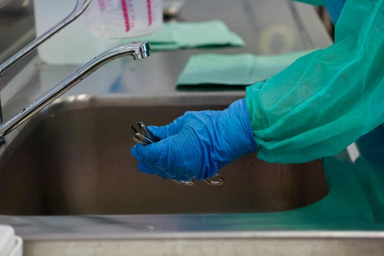medical staff at faucet with rubber gloves