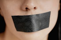Photo: Getty Images Close-up of a young woman with adhesive tape over her mouth