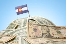 Photo: Getty Images The national flag of Colorado sticking in a pile of american dollars.(series)