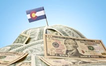 The national flag of Colorado sticking in a pile of american dollars.(series)