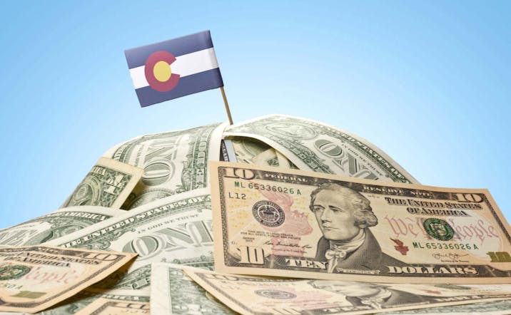 The national flag of Colorado sticking in a pile of american dollars.(series)