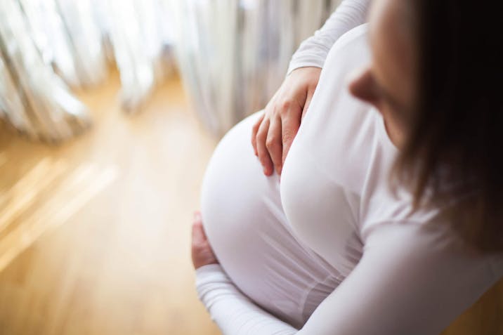 Photo: Getty Images A pregnant woman holds her bump feeling positive