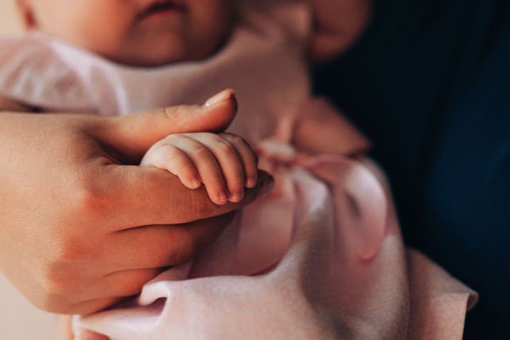 A close-up of a mother gently holding her baby's tiny hand, symbolizing love, care, and the precious bond of family. The soft tones and delicate details create a warm and emotional image, ideal for themes related to motherhood, parenting, and family values.