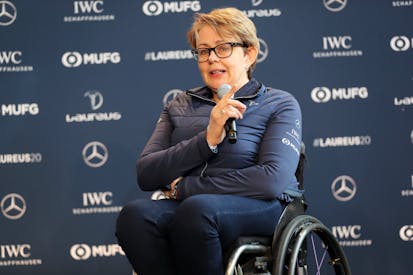 A woman in a wheelchair holds a microphone and gives a speech on stage.