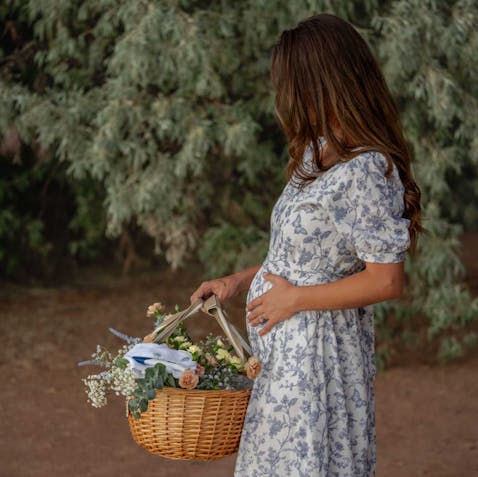 woman in dress holding baby bump