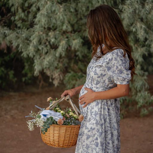 woman in dress holding baby bump