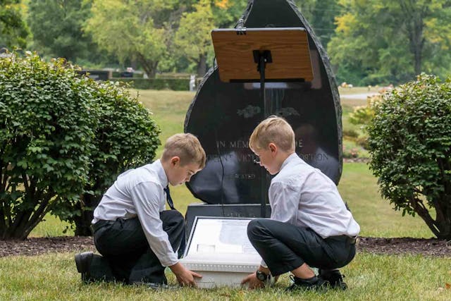 two young boys kneel in front of memorial for aborted babies