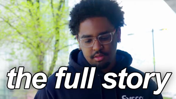 black man in dark blue sweatshirt, wearing glasses, caption: the full story