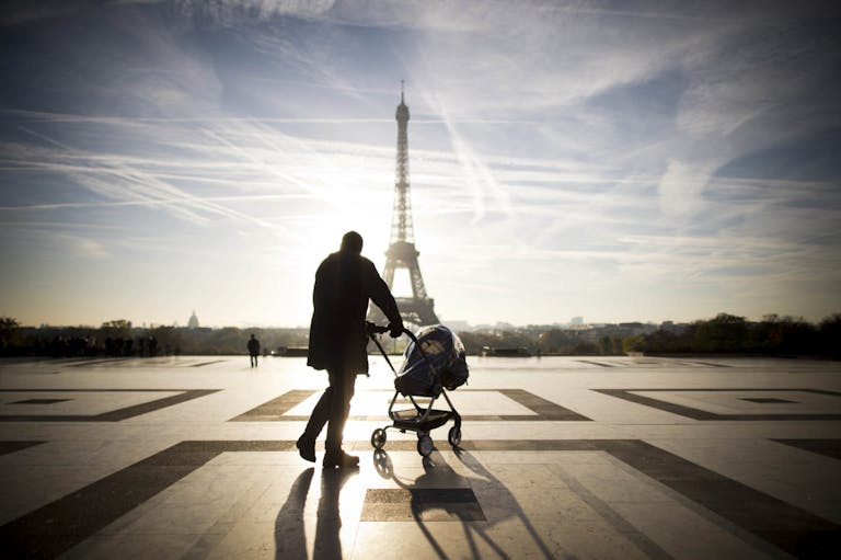 A person walks with baby-buggy in front of the Eiffel tower on November 11, 2013 at the Trocadero in Paris.