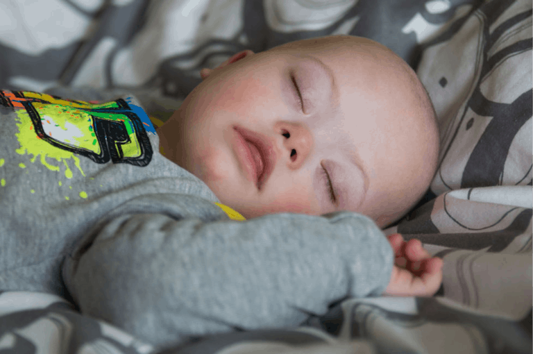 Close-Up Of Baby With Down Syndrome Sleeping On Bed