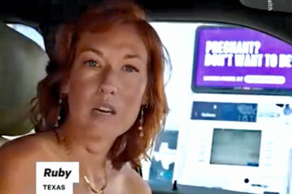 woman named Ruby sits next to purple abortion sign in her car