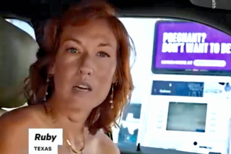 woman named Ruby sits next to purple abortion sign in her car