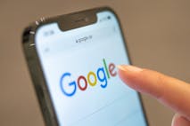 A woman holds a cellphone on the Google website.