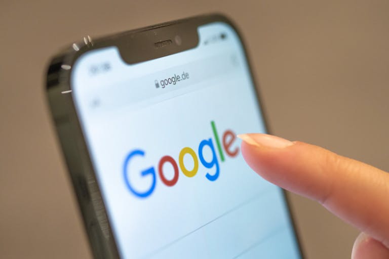 A woman holds a cellphone on the Google website.