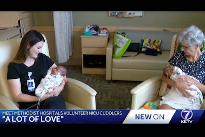 Two volunteers cuddle newborn premature twins Caden and Cason Phillips.