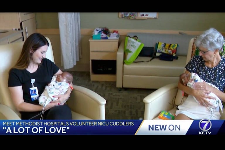 Two volunteers cuddle newborn premature twins Caden and Cason Phillips.
