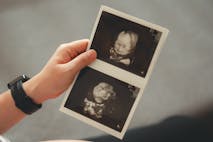 Photo: Jajah-sireenut/Getty Images Close-up shot of pregnant woman holding and looking at ultrasound scans, sitting on sofa in living room at home.