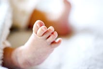 Photo: minianne/Getty Images Newborn baby on a white and light blue blanket - tiny baby feet closeup.