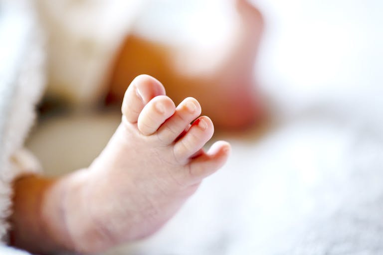 Photo: minianne/Getty Images Newborn baby on a white and light blue blanket - tiny baby feet closeup.